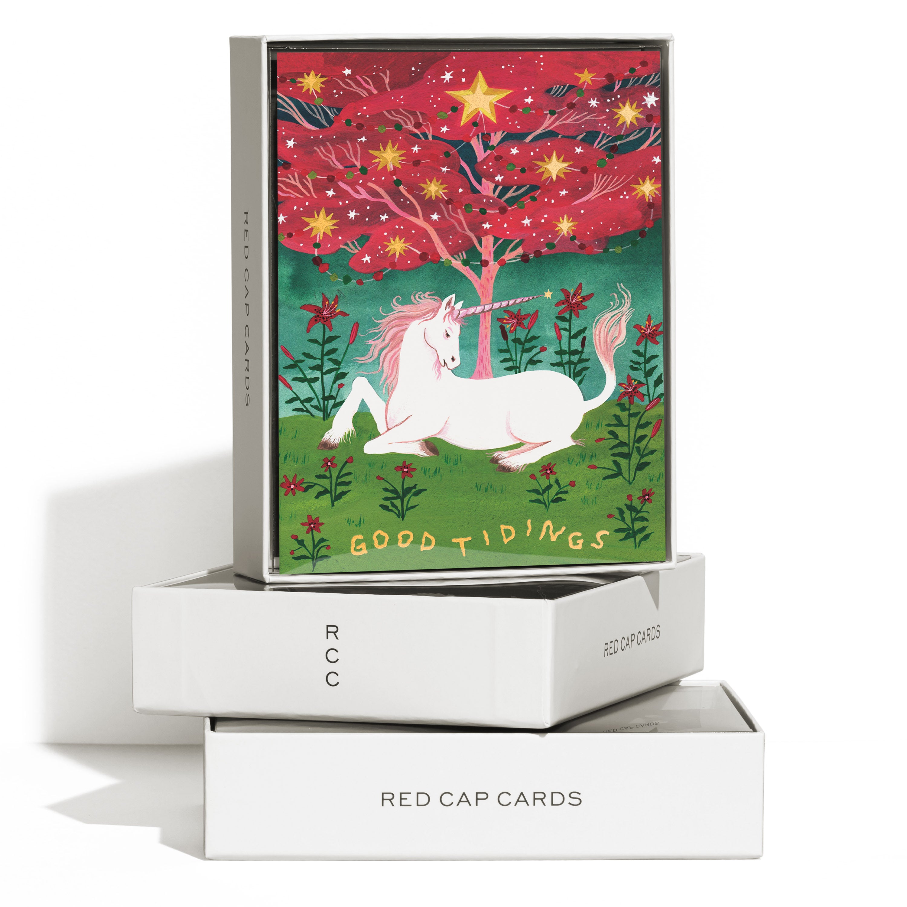 Boxed Set of 8 "Good Tidings" greeting cards featuring a unicorn under a tree in a grassy field of red flowers.