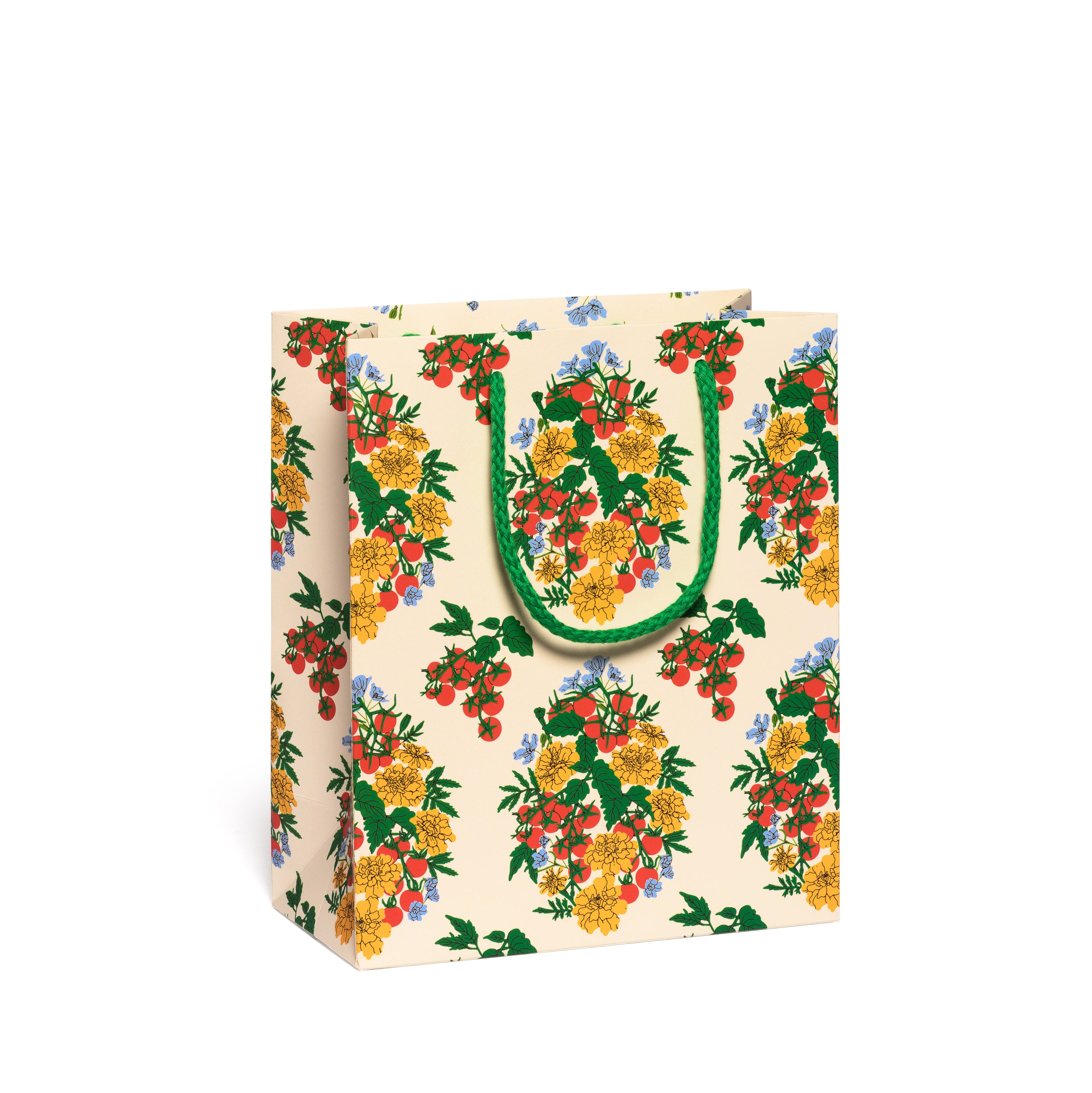Floral patterned gift bag with green handles on a white background.