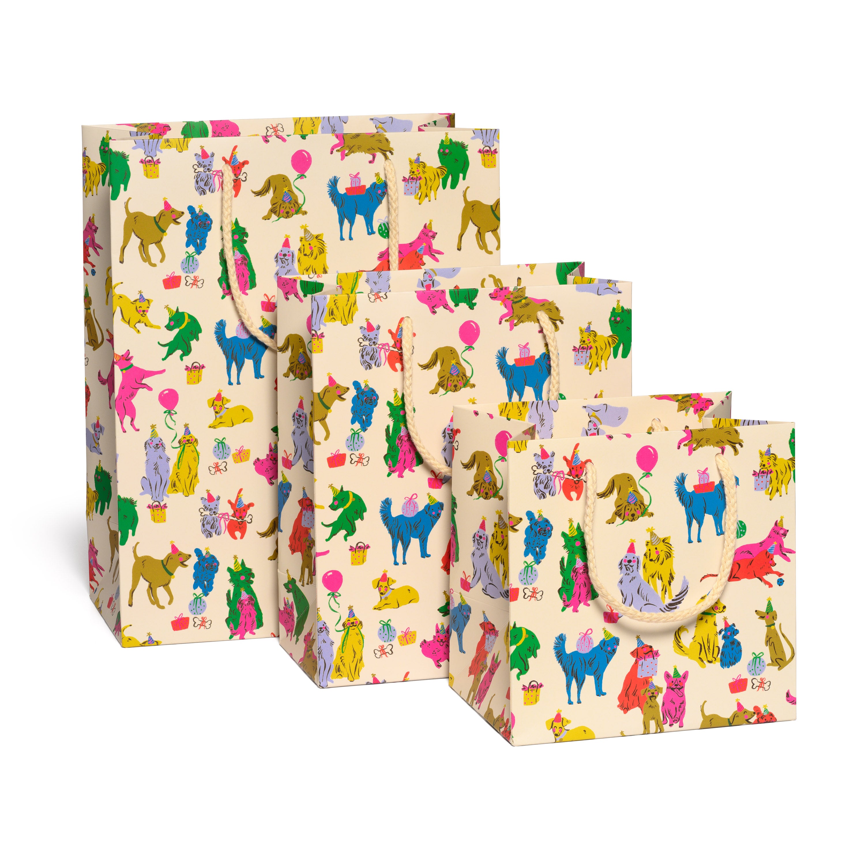 Set of three colorful gift bags with puppy party patterns on a tan background.