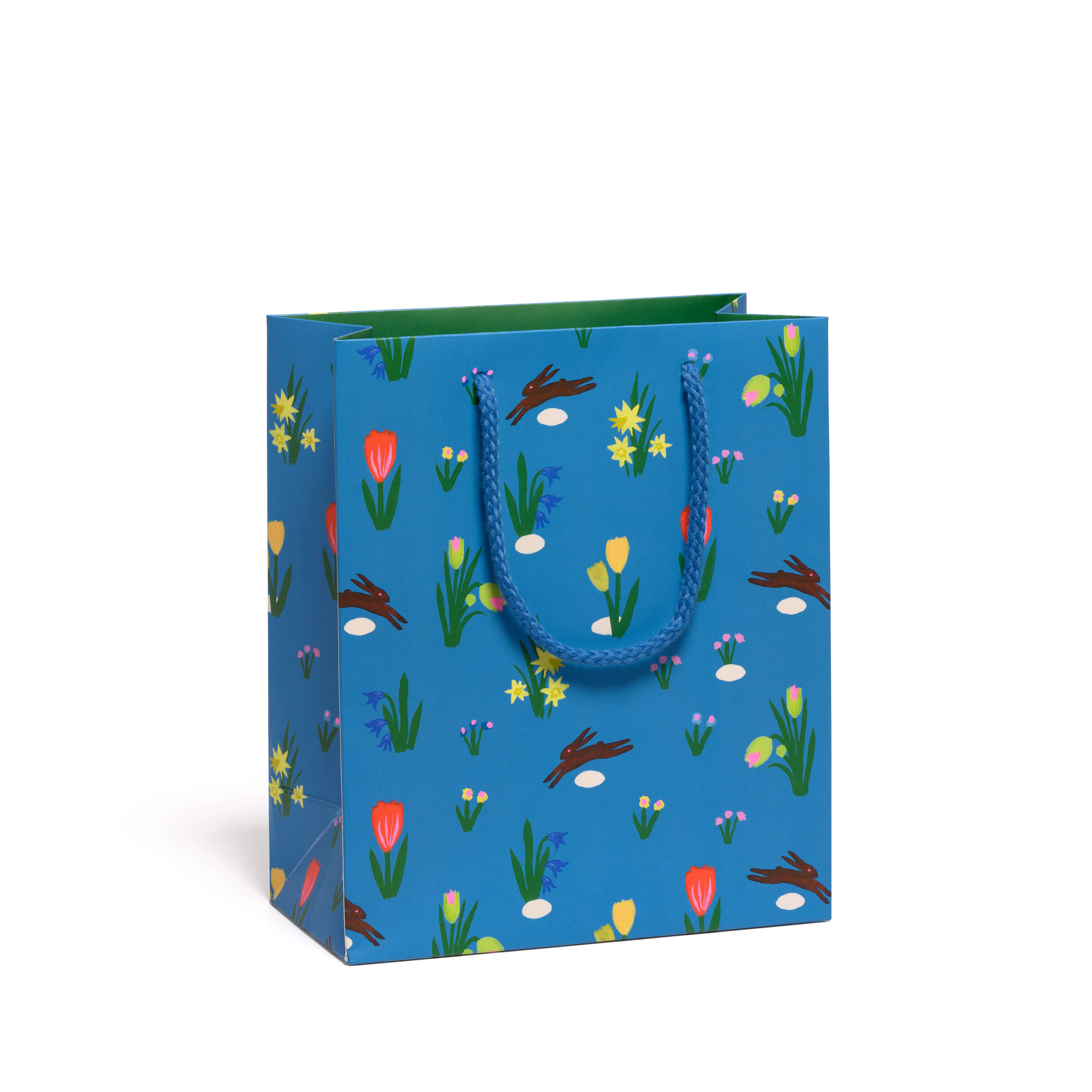 Blue gift bag with leaping brown bunny and floral pattern with blue rope handle on a white background.