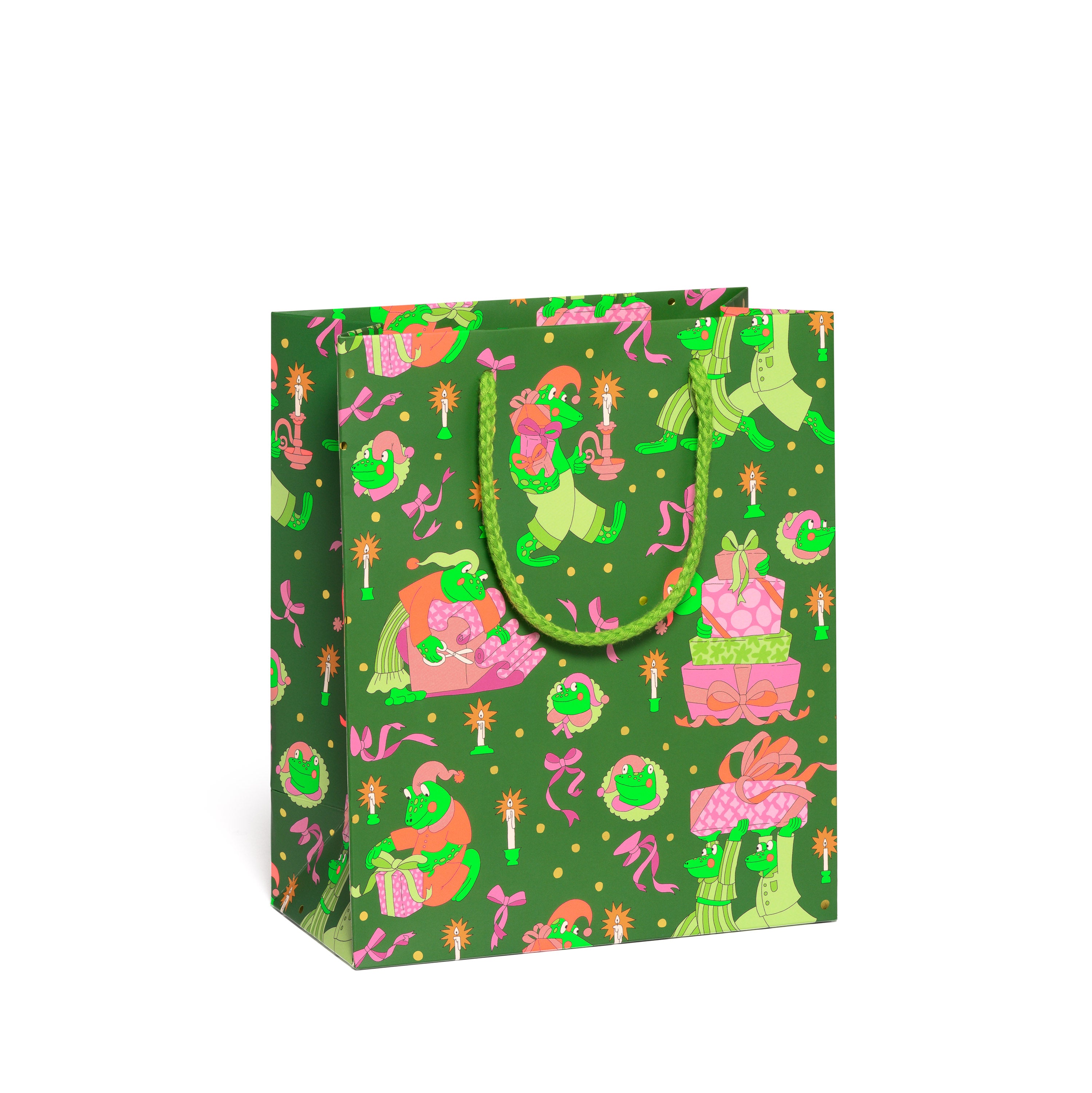 Green gift bag with a holiday pattern of festive frogs, wrapped presents, candles, and pink bows.