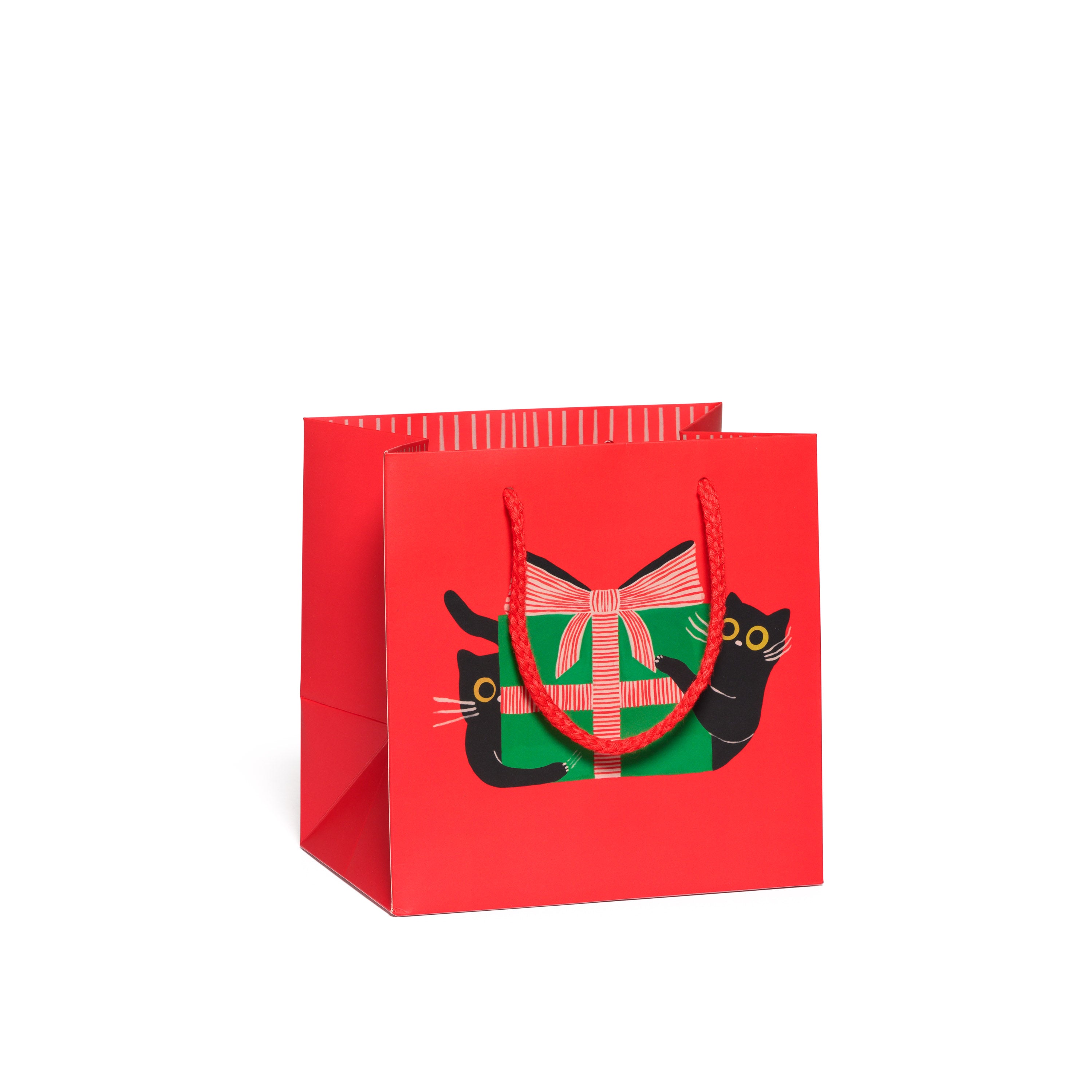 Red gift bag with a black cat with green present and red bow design with a red rope handle.