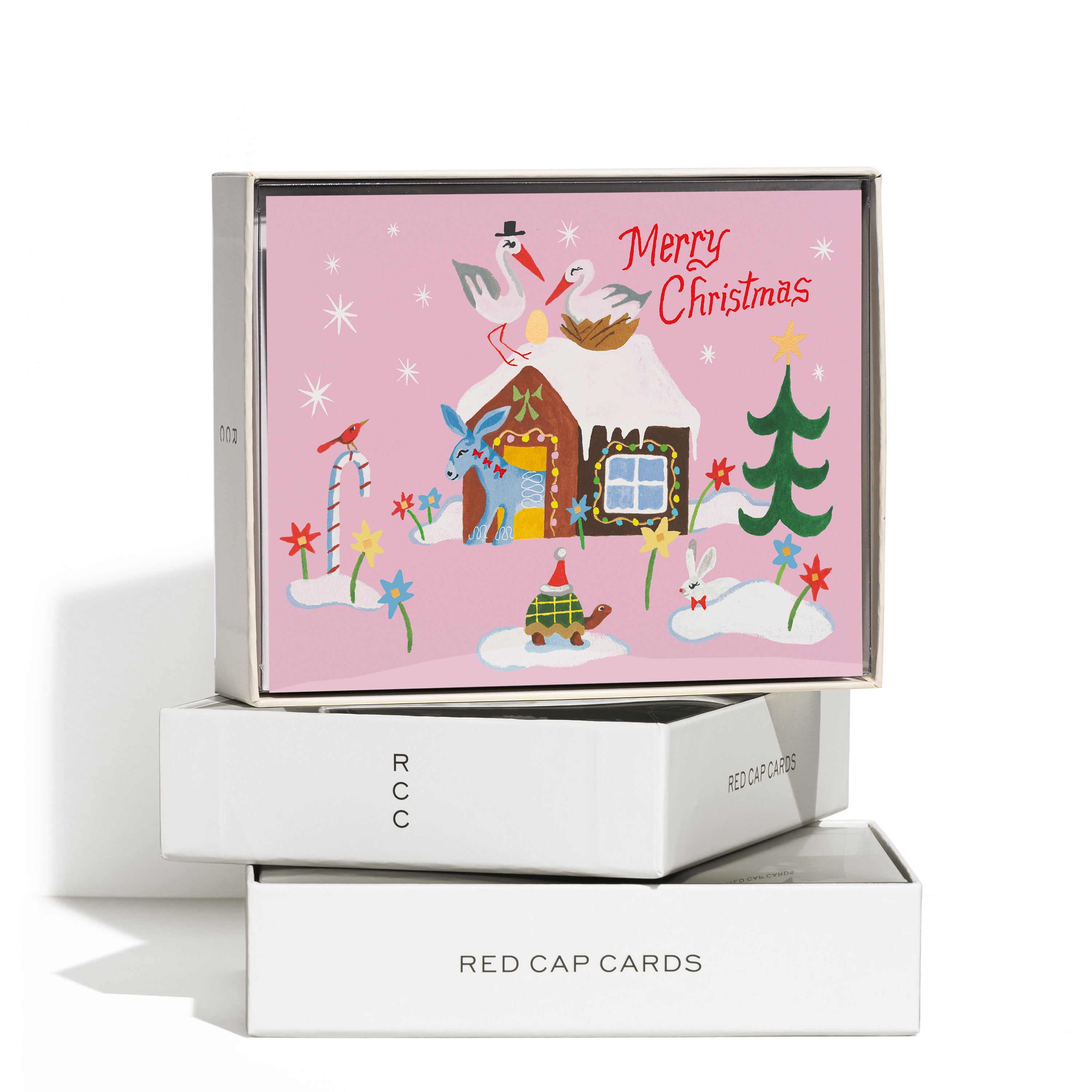 Boxed set of 8 pink Christmas greeting cards with illustrations of storks, a house, tree, flowers and 'Merry Christmas' text.