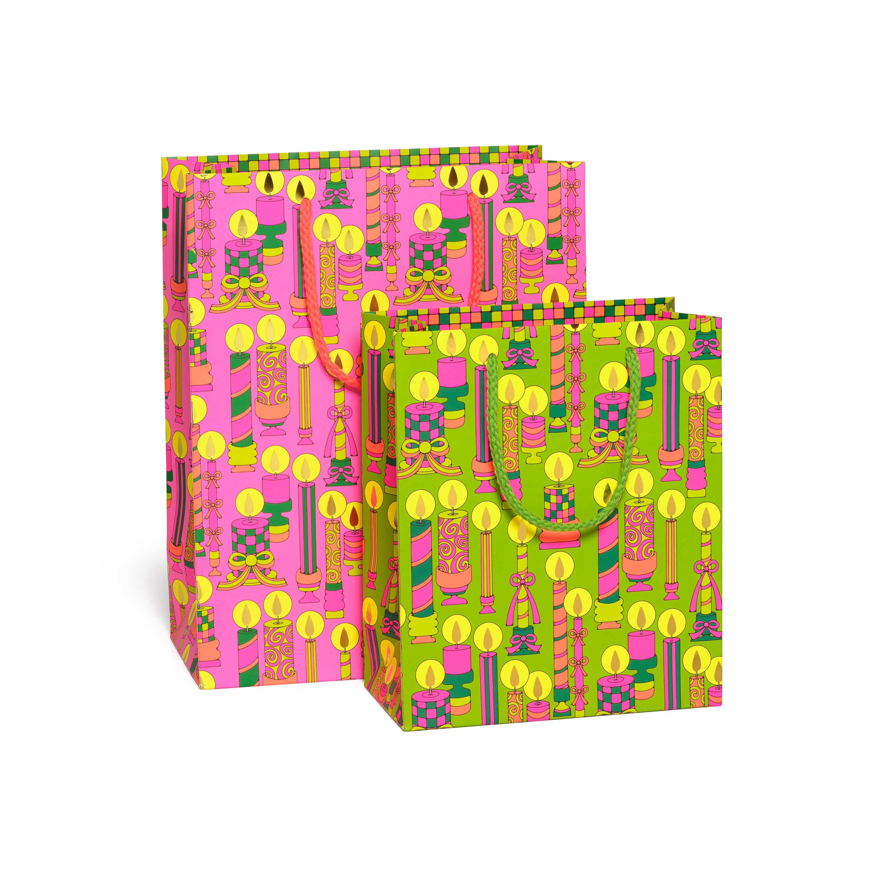 Two colorful gift bags with geometric Holiday Candle patterns on pink and green backgrounds.