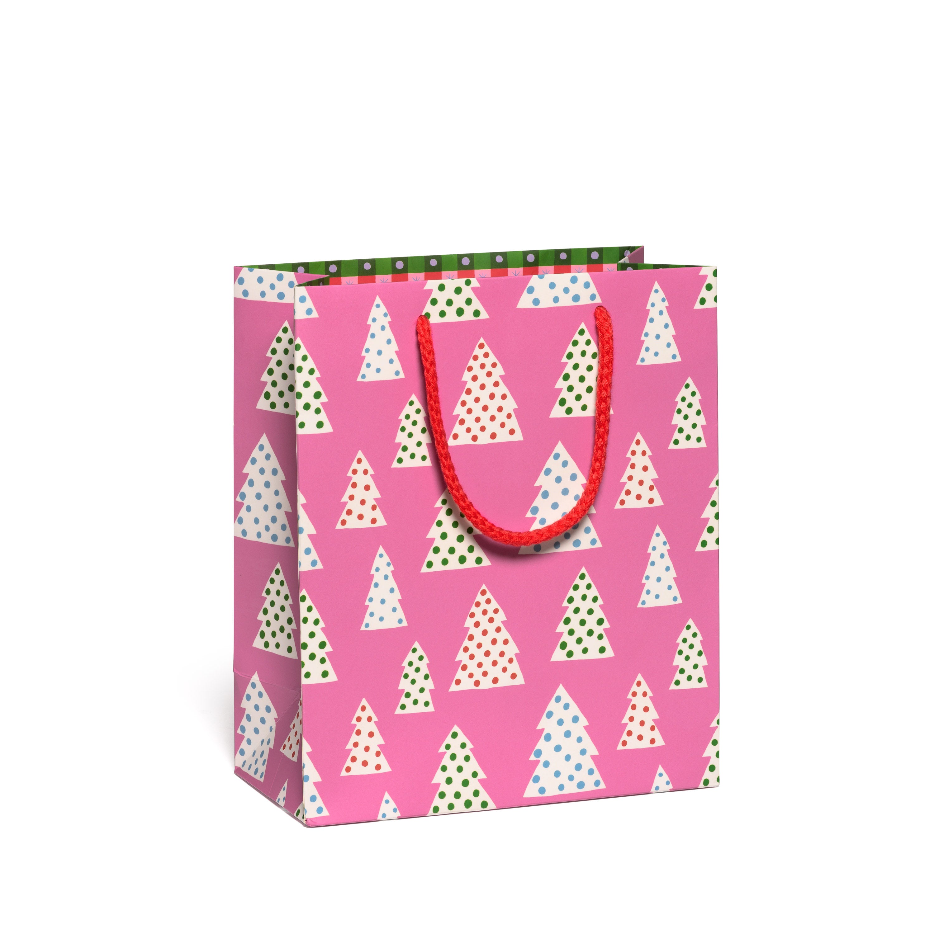 Gift bag with Christmas tree and polka dot pattern on a pink background.