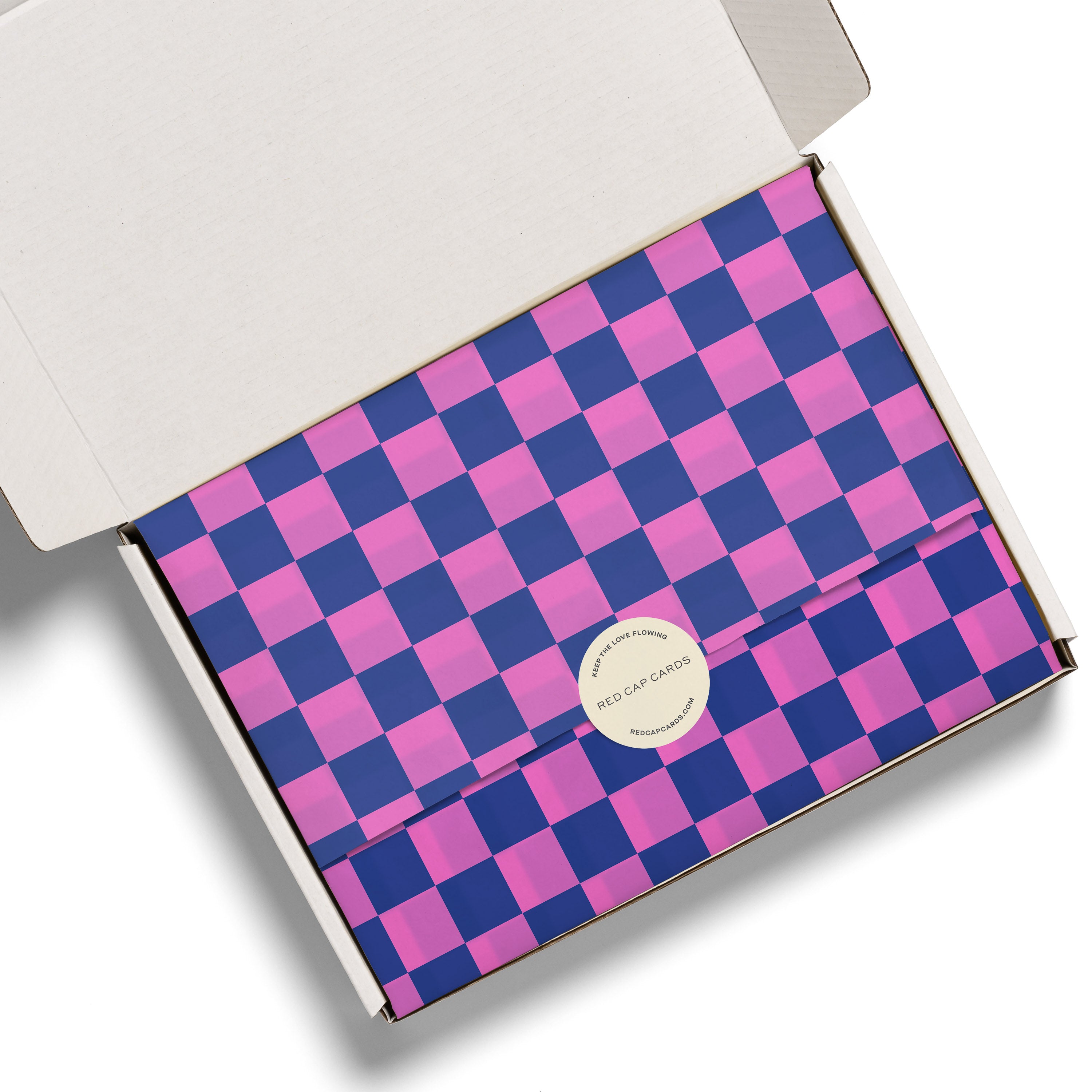 Checkered tissue paper with pink and blue pattern in a white gift box.
