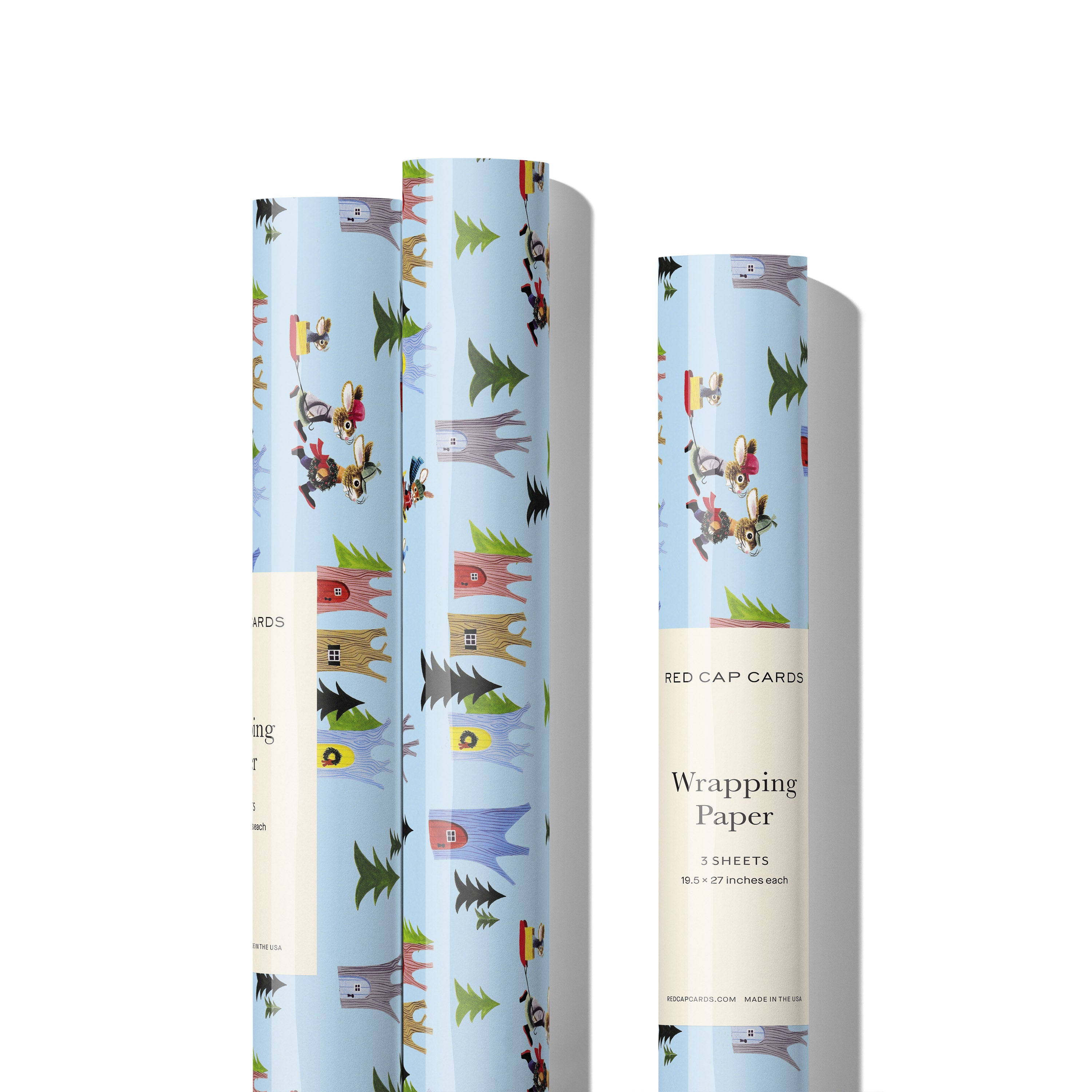 Three rolls of wrapping paper with cartoon woodland winter scene with rabbits and tree houses.
