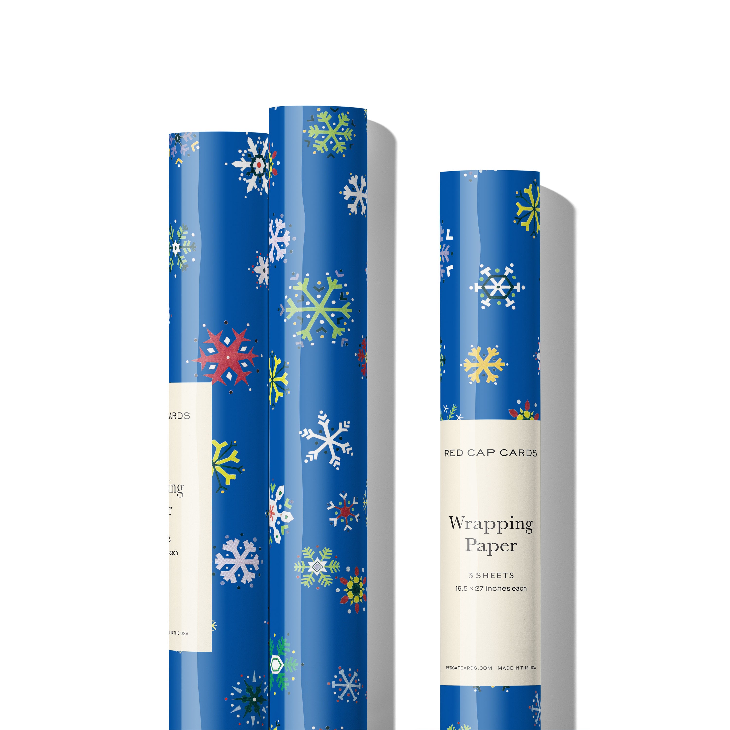 Three rolls of blue wrapping paper with colorful illustrated snowflake design on white background.