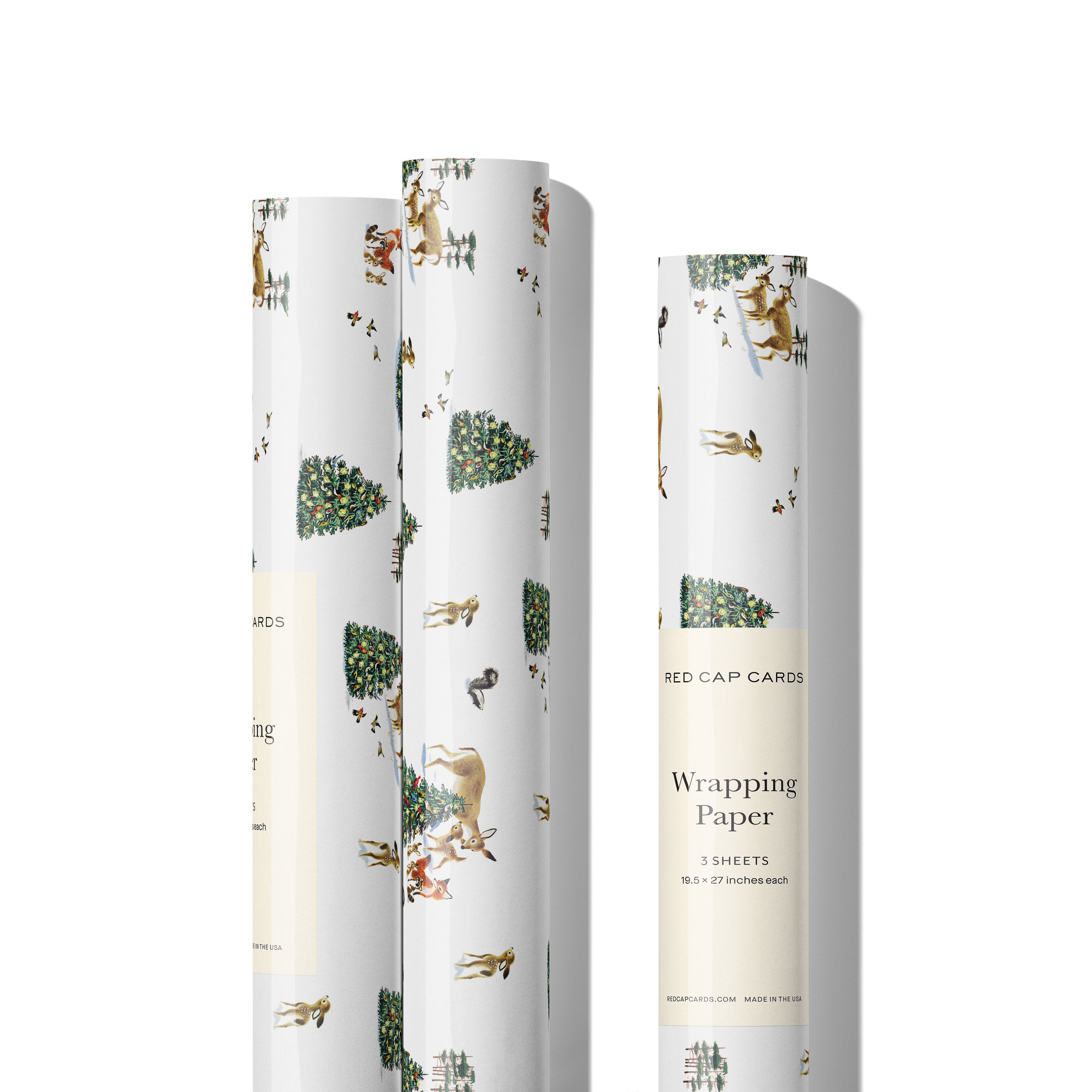 Three rolls of Wrapping paper with illustrated woodland snowy scene with Christmas tree and deer, foxes and skunks.