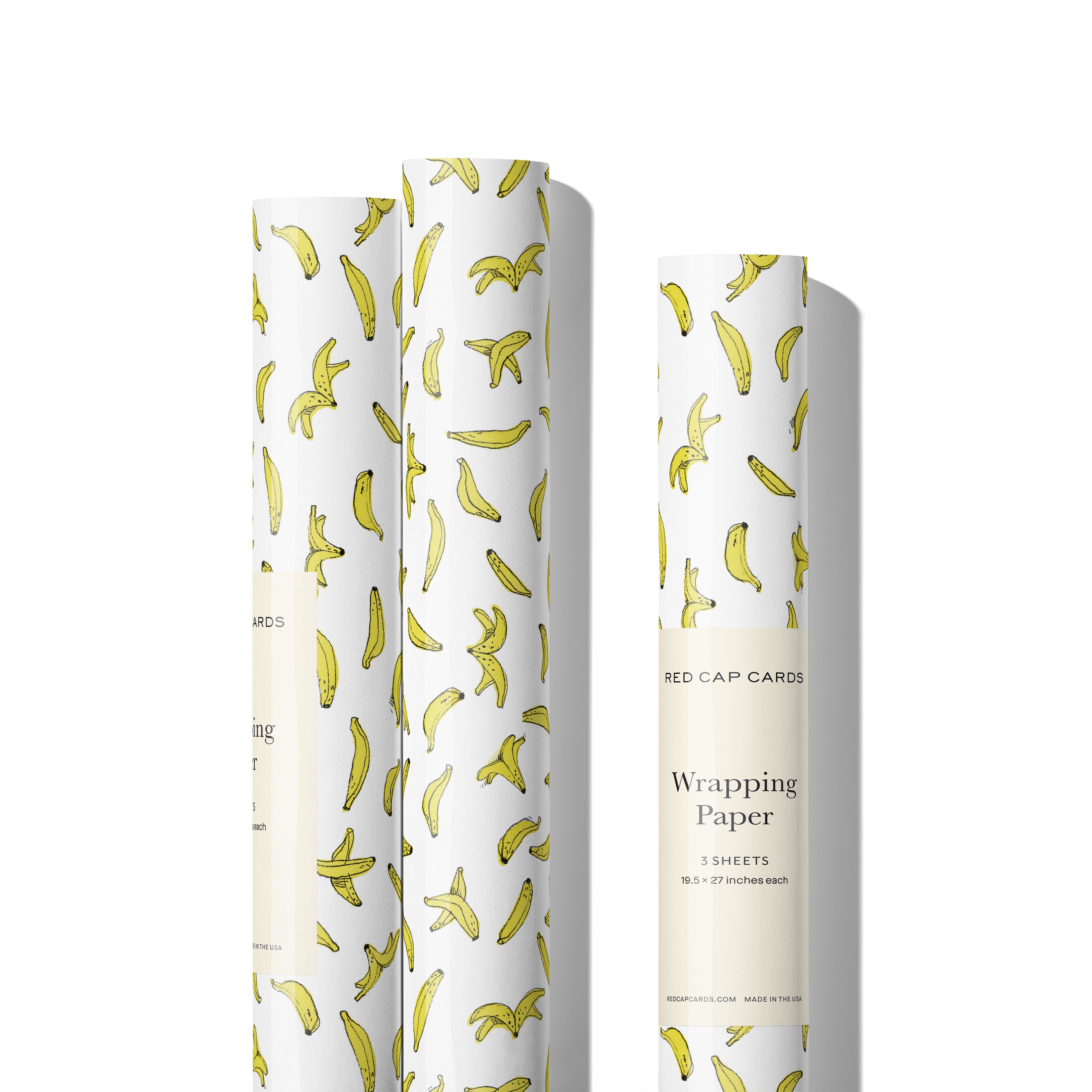 Three rolls of Gift Wrap with banana pattern on white background.