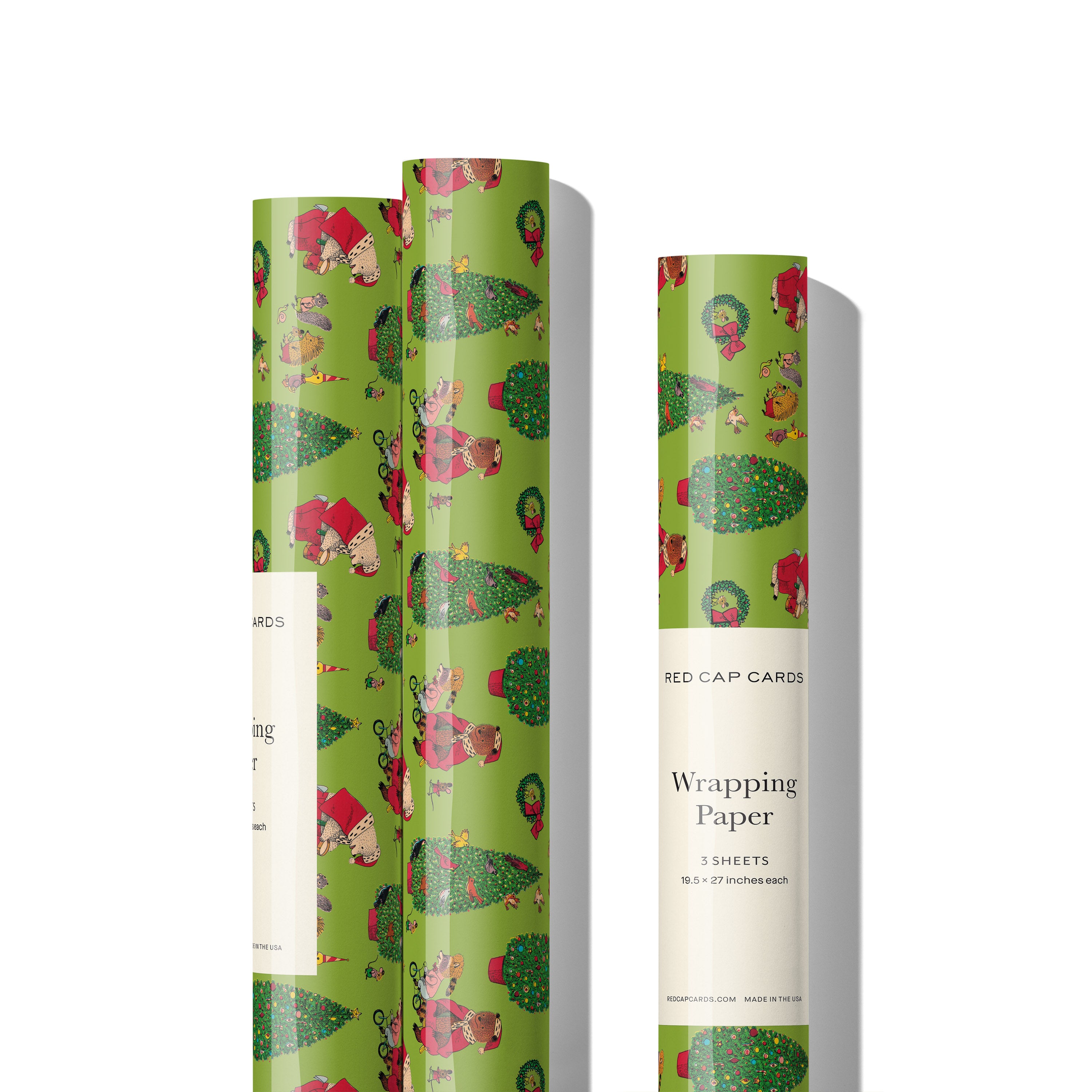 Three rolls of green wrapping paper with cartoon Christmas themes including a bear dressed as Santa on white background.