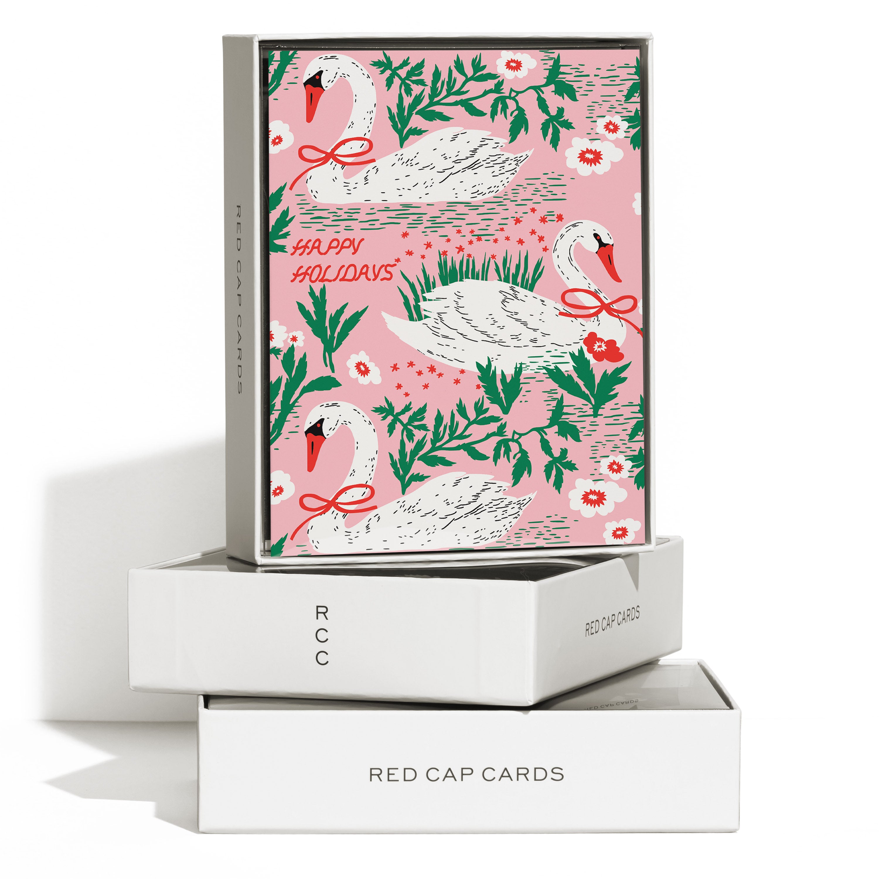 Boxed set of 8 Christmas cards with 3 illustrated swans in pink body of water and "Happy Holidays" text.
