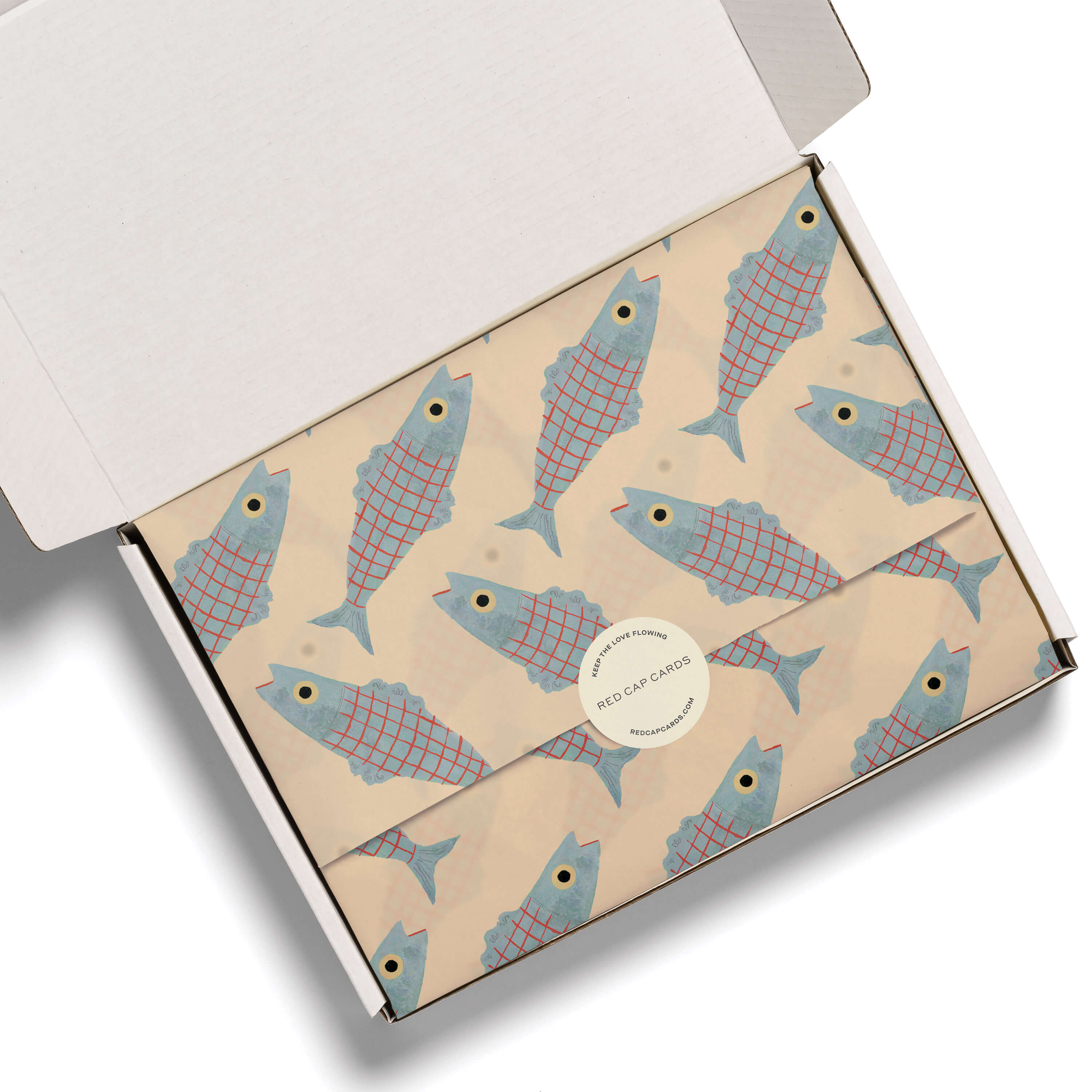 Beige tissue paper with a gray-blue and red striped Herring design nn a white box.