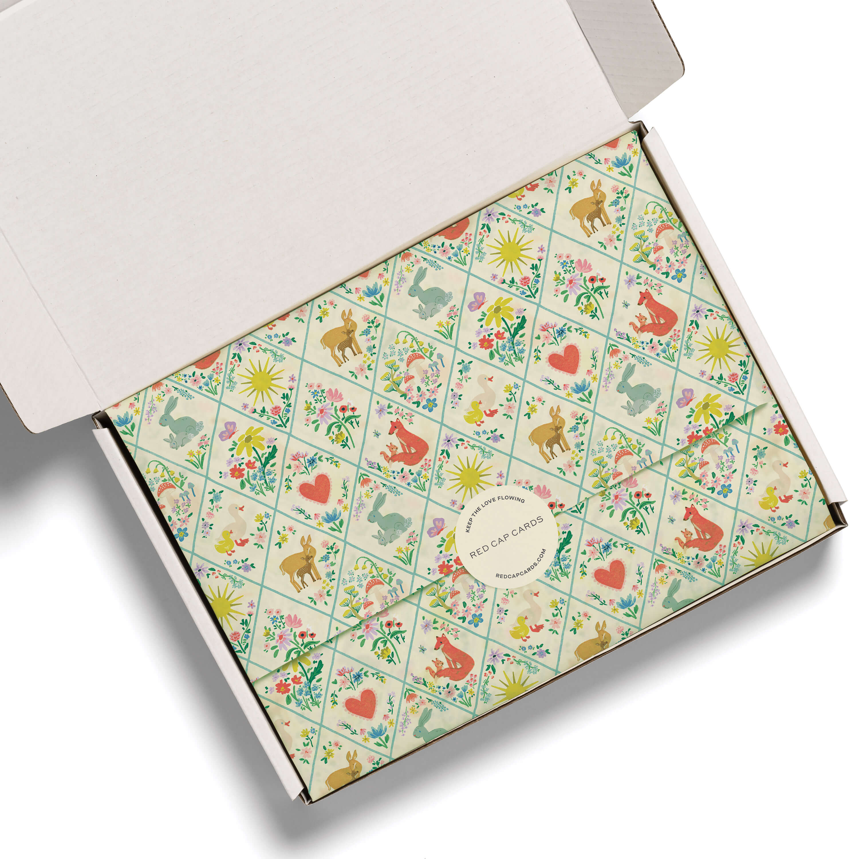Tissue paper with illustrated woodland critters quilted design  in a white gift box on a white background.