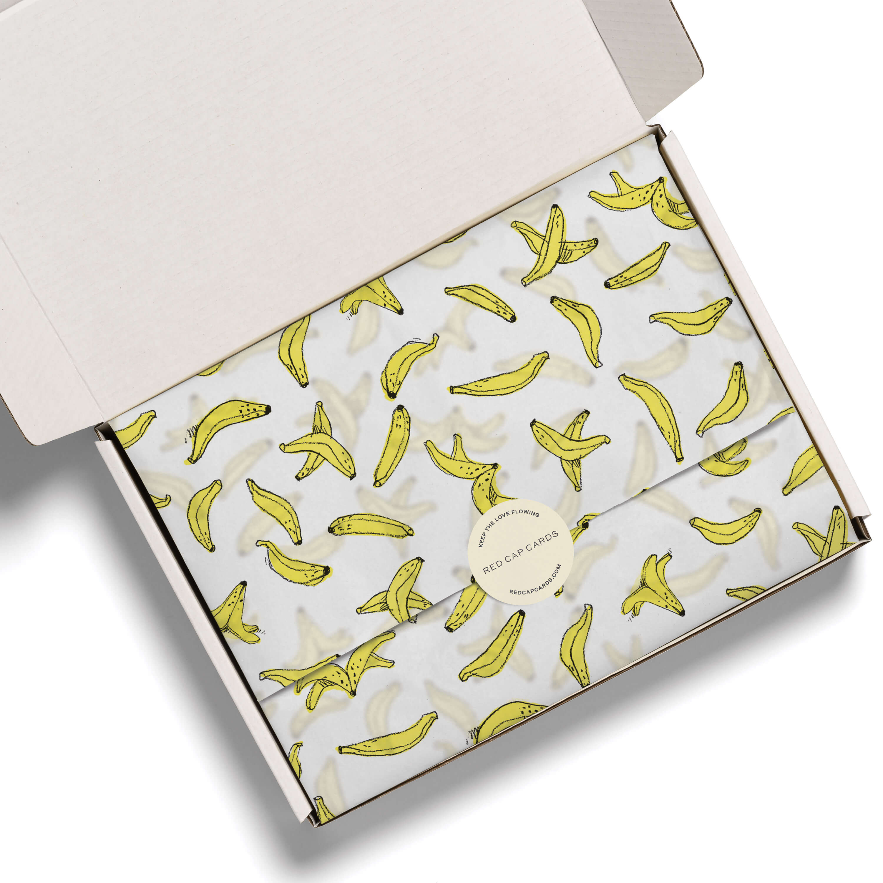Illustrated banana designed tissue paper in white gift box on a white background.